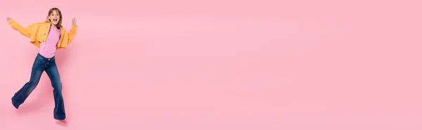 Панорамний Знімок Жінки Дивлячись Камеру Стрибаючи Рожевому Фоні — стокове фото