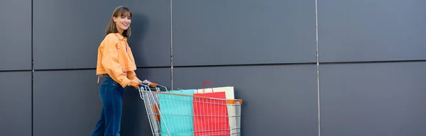 Panoramic Concept Young Woman Looking Camera Shopping Bags Cart Building — Stock Photo, Image