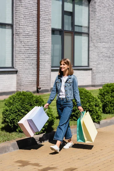 Jovem Mulher Jaqueta Jeans Segurando Sacos Compras Enquanto Caminhava Rua — Fotografia de Stock