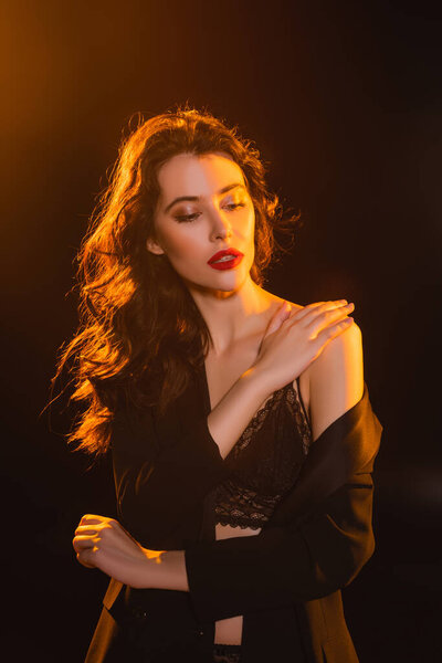 соблазнительная и кудрявая женщина касается кружевного бюстгальтера на черном 