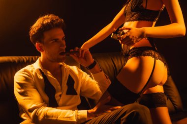 Baştan çıkarıcı kadın, elinde sigarası olan bir adamın yanında çakmak tutuyor. 