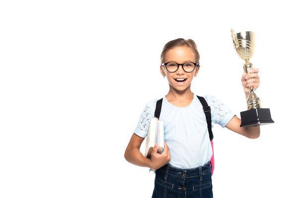 excited schoolkid in glasses holding books and golden trophy isolated on white 