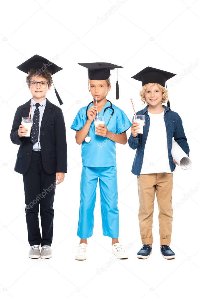 children in graduation caps dressed in costumes of different professions holding glasses with milk isolated on white 