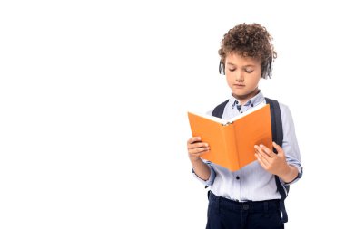 Kablosuz kulaklıklı kıvırcık okul çocuğu, beyaz kitap okuyor. 
