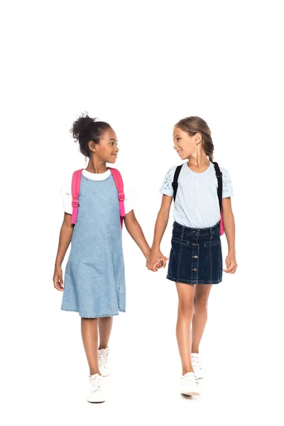 Multicultural Schoolgirls Backpacks Holding Hands Looking Each Other Isolated White — Stock Photo, Image