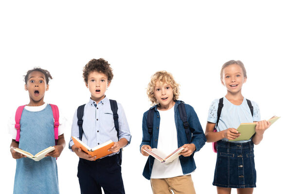multicultural and shocked schoolkids holding books isolated on white 