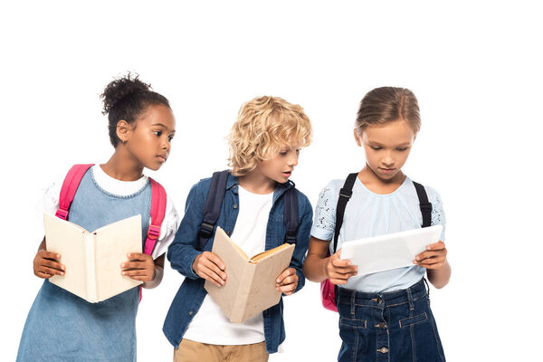 african american schoolgirl and blonde schoolboy with books looking at digital tablet in hands of classmate isolated on white 