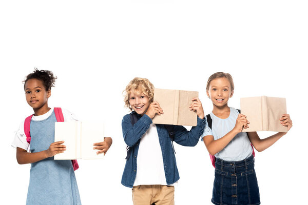 multicultural schoolgirls and curly schoolboy holding books isolated on white 