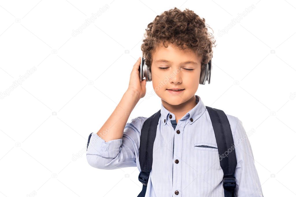 schoolboy with closed eyes touching wireless headphones isolated on white 