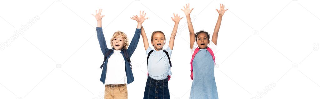 panoramic shot of excited multicultural schoolgirls and schoolboy with raised hands isolated on white 