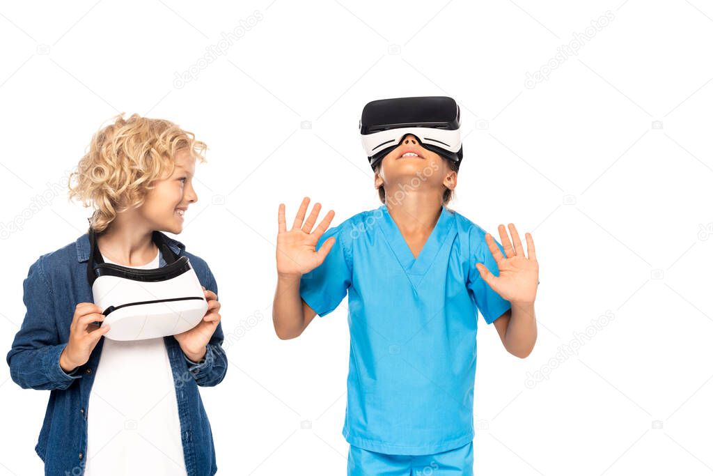 blonde boy looking at kid in virtual reality headset gesturing isolated on white 