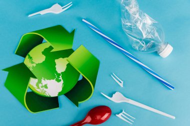 Mavi arkaplanda plastik çöpün yakınındaki geri dönüşüm sembolünün üst görünümü