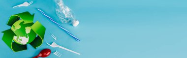 Mavi arkaplanda plastik çöpün yakınındaki geri dönüşüm sembolünün üst görünümü, panoramik çekim