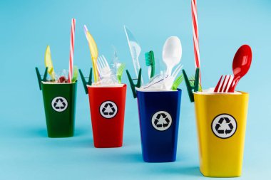 çok renkli geri dönüşüm kutuları ve mavi arka planda plastik