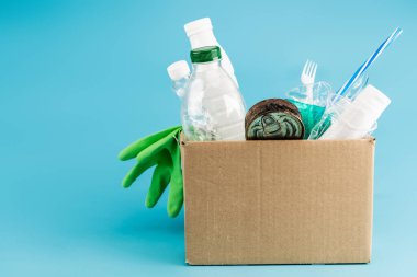 Mavi arka plandaki karton kutuda plastik çöp ve lastik eldivenler.