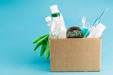 plastic rubbish and rubber gloves in cardboard box on blue background clipart