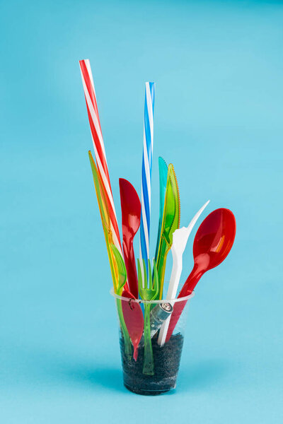 одноразовые столовые приборы и молотый в пластиковой чашке на синем фоне