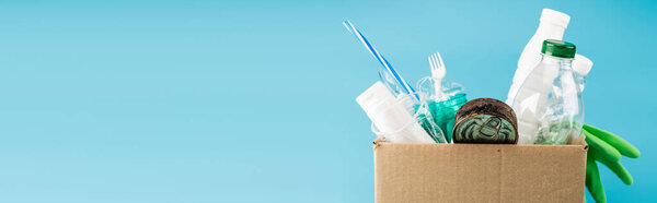 plastic rubbish and rubber gloves in cardboard box isolated on blue, panoramic shot