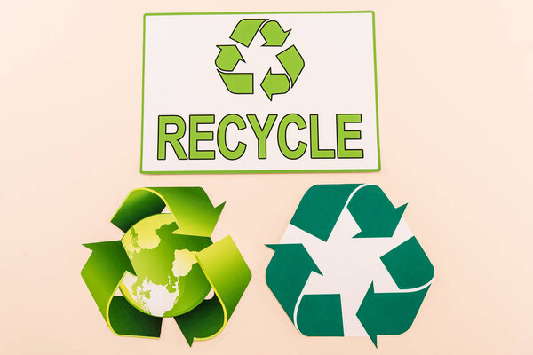 top view of green recycling symbols with planet and recycle word isolated on beige