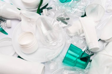 Beyaz arkaplana saçılmış plastik çöplerin üst görünümü