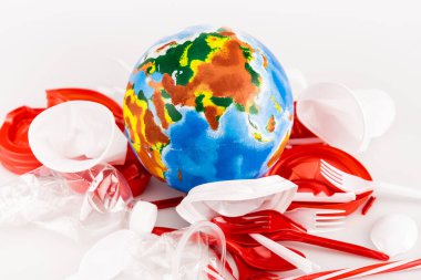 plastic trash scattered around globe on white background clipart