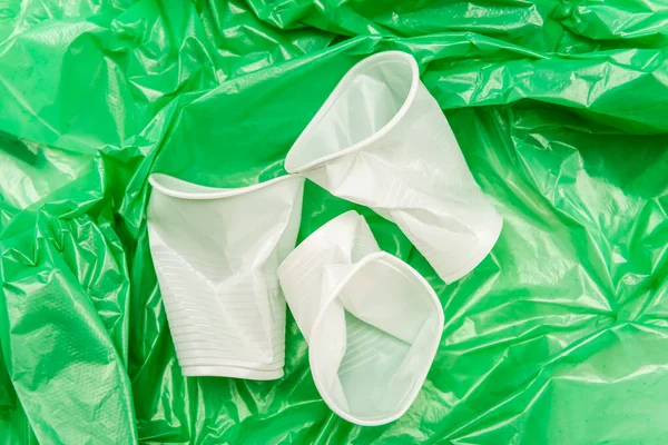 Bovenaanzicht Van Witte Verkreukelde Wegwerpbekers Groene Plastic Textuur — Stockfoto