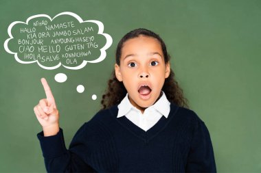 Şok olmuş Afrikalı Amerikalı okul kızı uluslararası dilleri olan düşünce balonunu işaret ediyor yeşil karatahta
