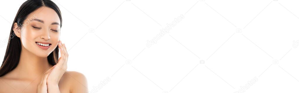 Panoramic shot of excited young asian woman with closed eyes touching face isolated on white