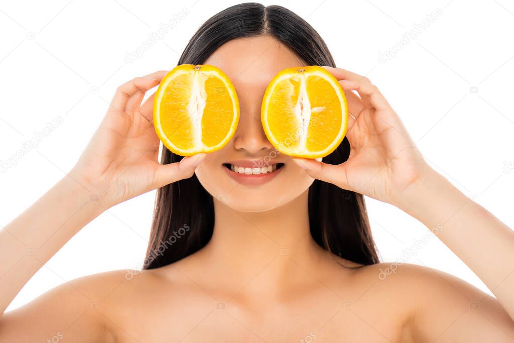 brunette woman covering eyes with halves of juicy orange isolated on white