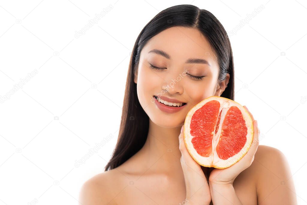 naked asian woman with closed eyes holding half of juicy grapefruit isolated on white