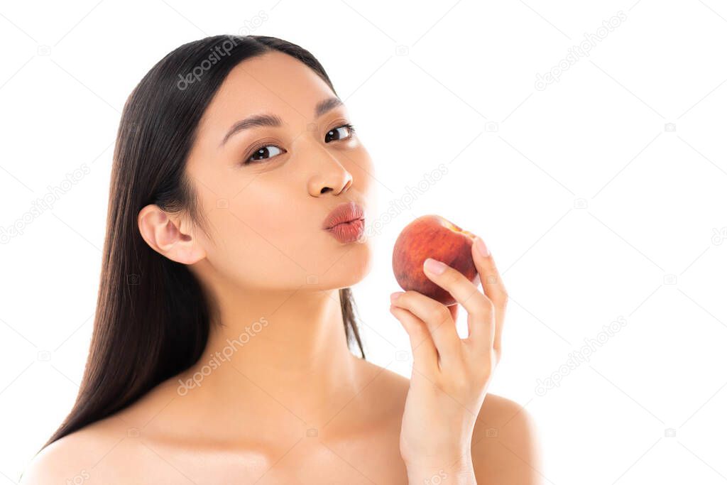 nude asian woman making duck face while holding whole peach isolated on white