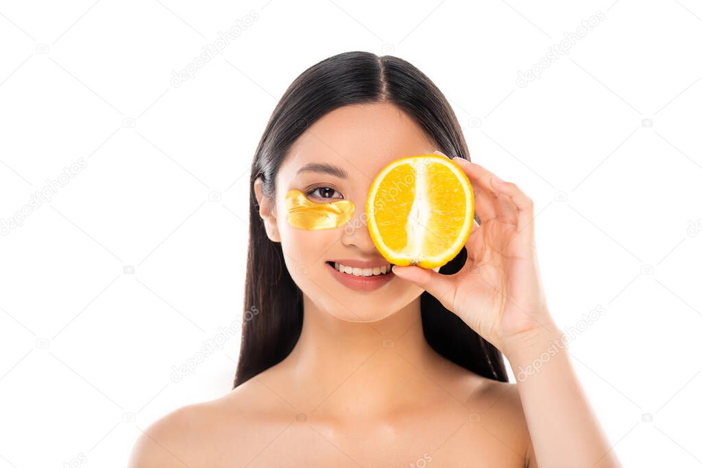 brunette asian woman with golden cosmetic patch covering eye with half of ripe orange isolated on white