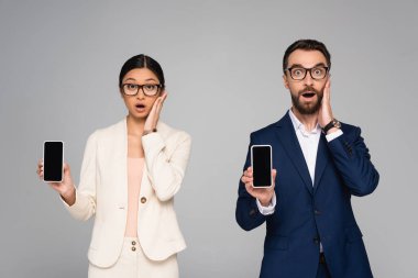 Gri ekranda boş ekranlı akıllı telefonları tutarken yüzlerine dokunan iki iş arkadaşına şaşırdım.