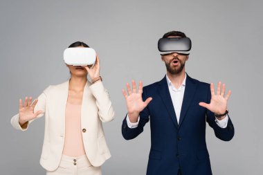 VR kulaklıklı heyecanlı iş adamları, gri bir şeye dokunur gibi el kol hareketi yapıyorlar.