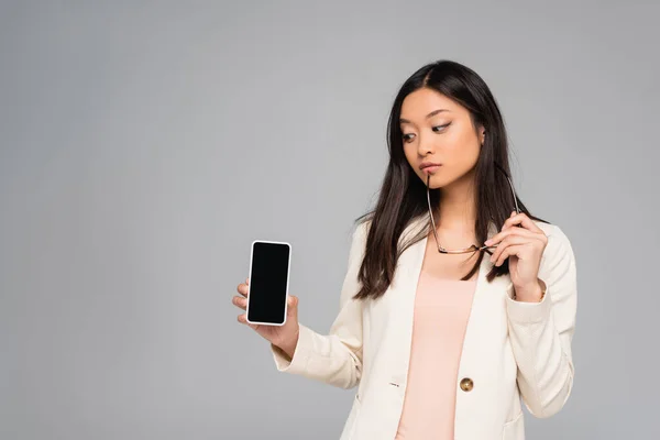 Thoughtful Asian Businesswoman Blazer Holding Eyeglasses While Showing Smartphone Blank — Stock Photo, Image