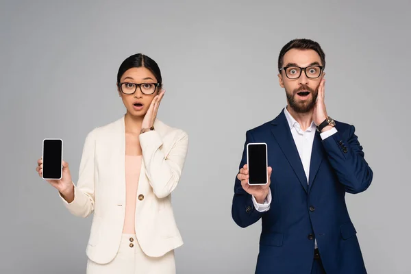 Surprised Interracial Couple Business Colleagues Touching Faces While Holding Smartphones — Stock Photo, Image