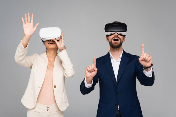excited business partners in vr headsets gesturing like touching something isolated on grey