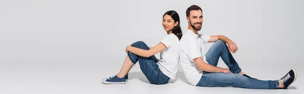 Panoramic Concept Stylish Interracial Couple White Shirts Jeans Gumshoes Sitting — Stock Photo, Image