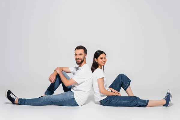 Young Interracial Couple White Shirts Jeans Gumshoes Looking Camera While — Stock Photo, Image