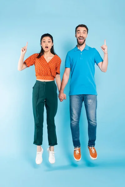 Excited Asian Couple Holding Hands Showing Idea Gesture While Levitating — Stock Photo, Image