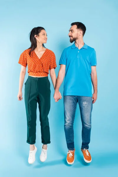 Stylish Interracial Couple Holding Hands Looking Each Other While Levitating — Stock Photo, Image