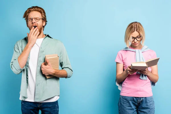 Pelirroja Hombre Bostezando Cubriendo Boca Mientras Estudiante Rubia Leyendo Libro — Foto de Stock