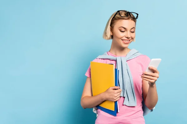 Blonde Studentin Hält Notizbücher Der Hand Und Benutzt Smartphone Auf — Stockfoto