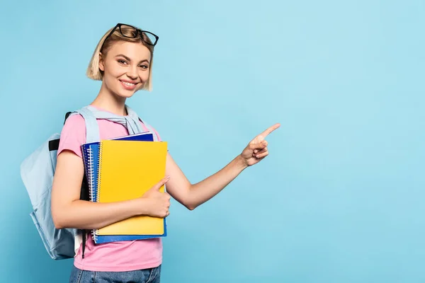 Young Blonde Student Backpack Holding Notebooks Ponging Finger Blue — Stock Photo, Image