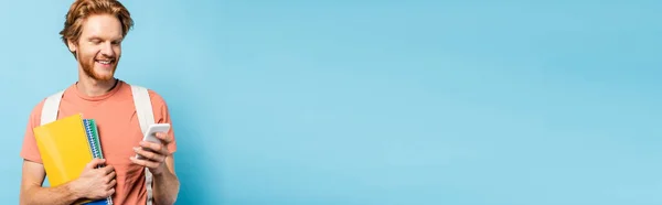 Горизонтальний Урожай Рудого Студента Тримає Блокноти Використовує Смартфон Синьому — стокове фото