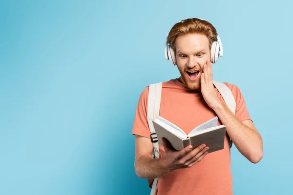 Podekscytowany Rudy Student Słuchawki Bezprzewodowe Czytanie Książki Niebieski — Zdjęcie stockowe