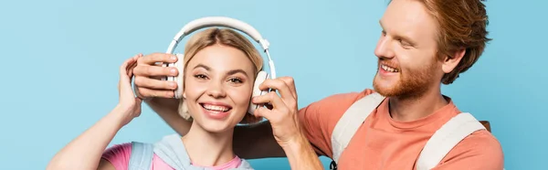 Panoramic Shot Bearded Student Touching Wireless Headphones Blonde Friend Blue — Stock Photo, Image