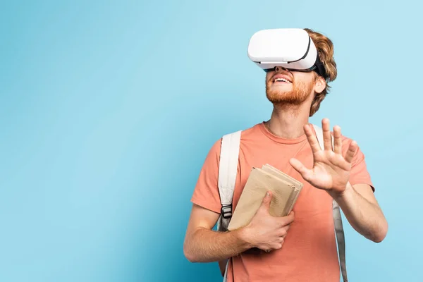 Young Redhead Student Virtual Reality Headset Holding Books Gesturing Blue — Stock Photo, Image
