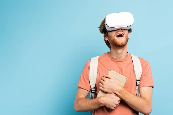 Excited Redhead Student Virtual Reality Headset Holding Books Gesturing Blue — Stock Photo, Image