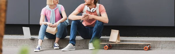 Panoramic Crop Students Glasses Sitting Skateboard Gadgets While Looking Each — Stock Photo, Image